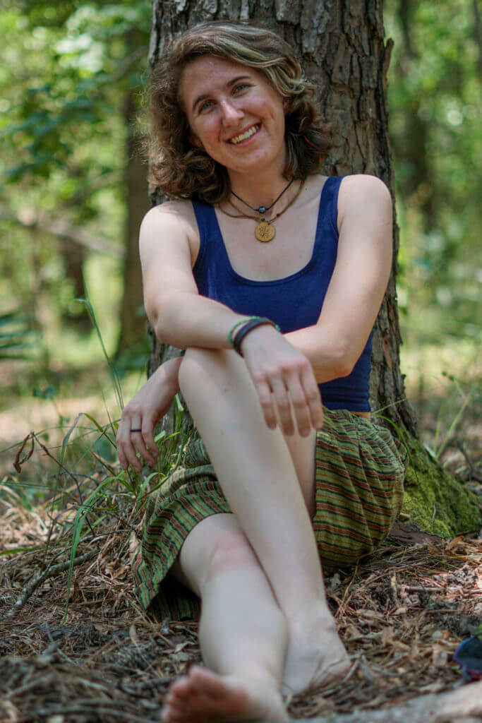 Model wearing navy blue crop tank with striped green hippie shorts against tree