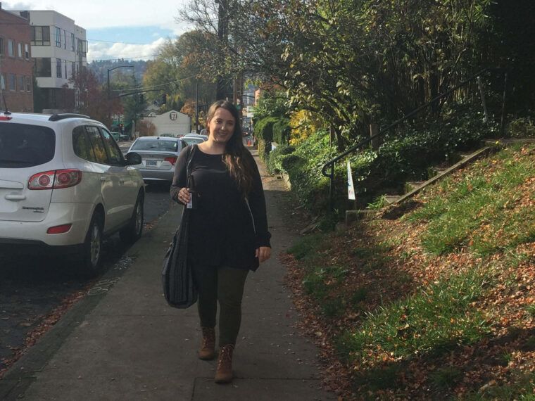 A woman with an eco boho vibe walks on a sidewalk beside parked cars and a grassy hill with autumn trees under a partly cloudy sky. Soul Flower Blog: Hippie Style & Kind Living