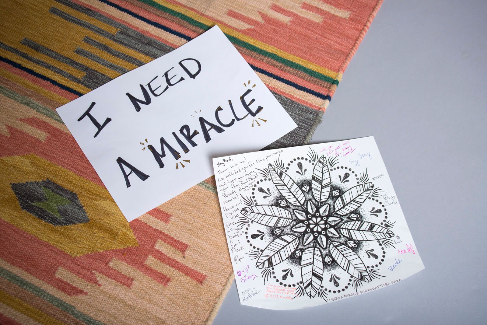 A handwritten sign reading I NEED A MIRACLE rests beside a mandala drawing, surrounded by colorful hippie notes on a boho-patterned rug. Soul Flower Blog: Hippie Style & Kind Living