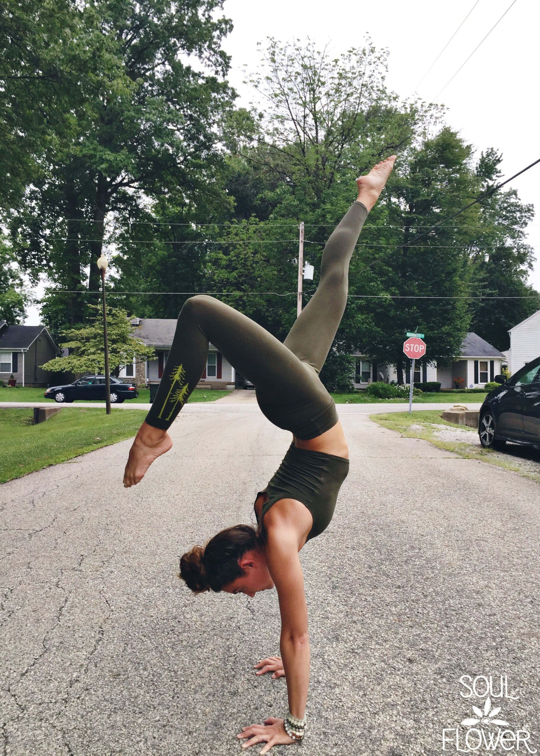 A person in olive green activewear performs a handstand split on a residential street lined with trees and houses. Soul Flower is written in the bottom right corner—Win the Two Pines Leggings!. Soul Flower Blog: Hippie Style & Kind Living