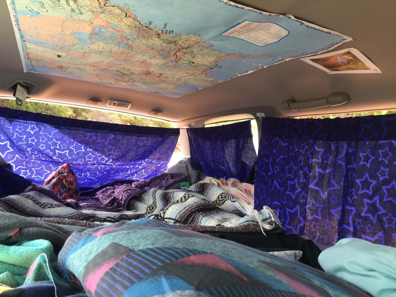 The interior of a car is set up for sleeping in true Bilbo Baggins Style - Car Livin', with star-patterned curtains, cozy blankets, and a map of North America taped to the ceiling. Soul Flower Blog: Hippie Style & Kind Living