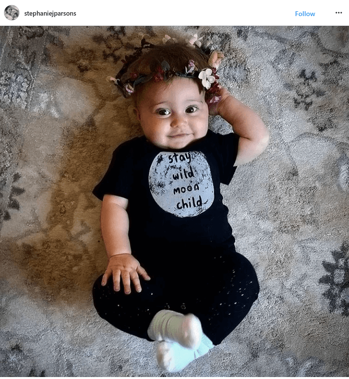 A baby wearing a flower crown and a black t-shirt that says stay wild moon child lies on a patterned rug, looking up with one hand behind their head. #soulflowerbuds Customer Love!. Soul Flower Blog: Hippie Style & Kind Living