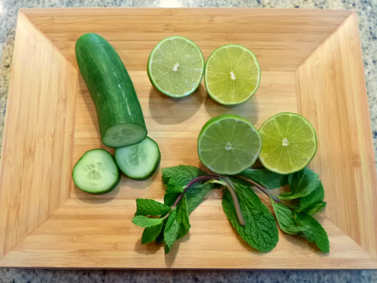 A wooden tray with a partially sliced cucumber, two limes cut in half, and a small bunch of fresh mint leaves creates an earthy vibe, perfect for those who love natural flavors and funky presentations. Soul Flower Blog: Hippie Style & Kind Living