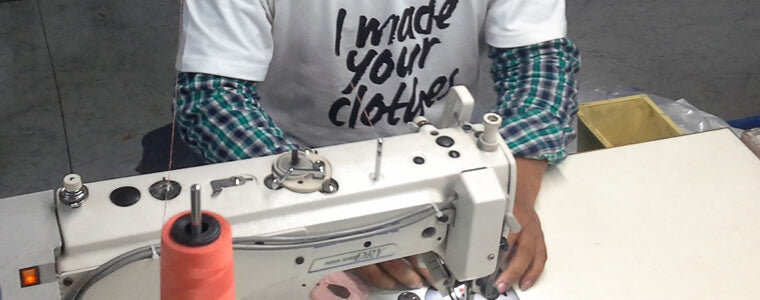 Celebrate Fair Trade Month with a person proudly wearing a shirt that says "I made your clothes" while skillfully operating a sewing machine threaded with orange spool. Soul Flower Blog: Hippie Style & Kind Living