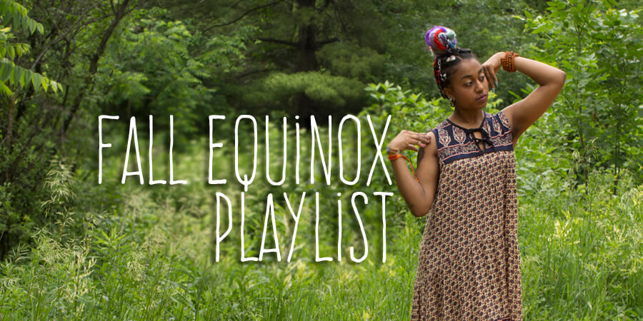A woman stands in a grassy, wooded area wearing a funky patterned dress, with text reading Fall Equinox Playlist overlaid on the image. Soul Flower Blog: Hippie Style & Kind Living