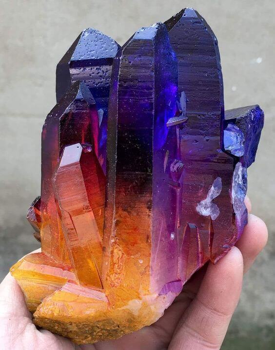 A hand holds a cluster of quartz crystals with a gradient of vibrant colors—yellow, orange, red, purple, and blue—inspired by Top Pins June-July 2016. Soul Flower Blog: Hippie Style & Kind Living