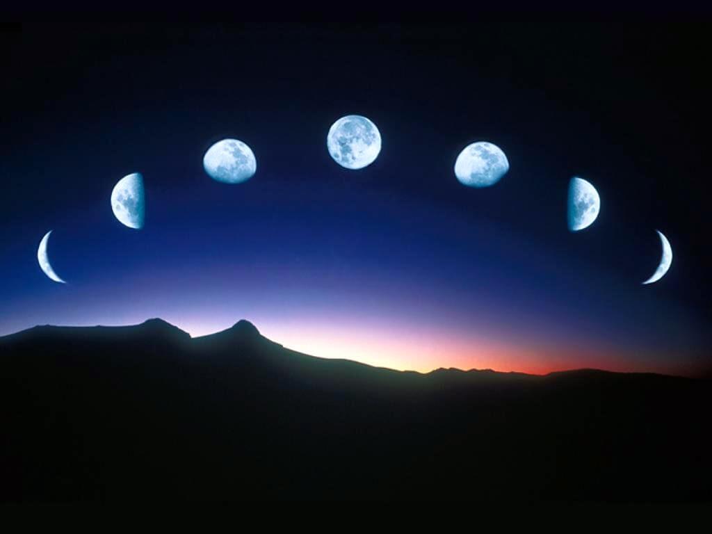 A sequence of moon phases displayed in an arc over a dark mountain landscape at dusk, creating a dreamy boho vibe. Soul Flower Blog: Hippie Style & Kind Living