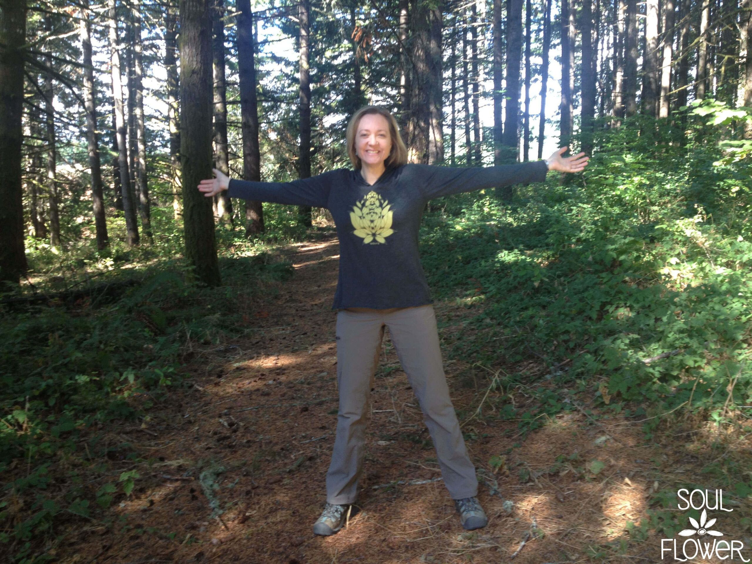 A person standing on a forest trail with arms outstretched, embracing The Call of the Wild. Dressed in a dark long-sleeve shirt and light pants. Soul Flower Blog: Hippie Style & Kind Living