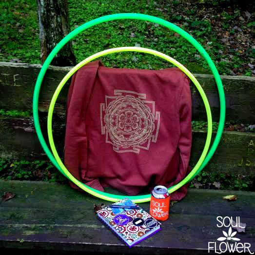 Two hula hoops, a maroon shirt with a geometric design, a can, and a notebook rest on a weathered wooden bench outdoors—perfect for inspiration and exploration. Soul Flower Blog: Hippie Style & Kind Living