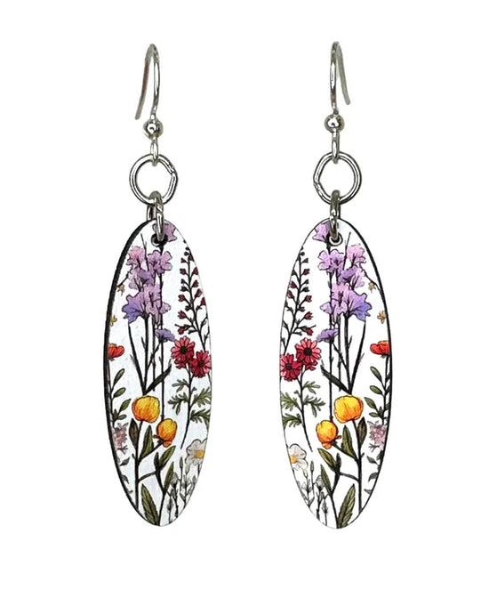 A pair of dangling earrings with oval white enamel pendants featuring a colorful botanical illustration of purple flowers, red blossoms, yellow-orange berries, and green stems, suspended from silver fishhook wires.